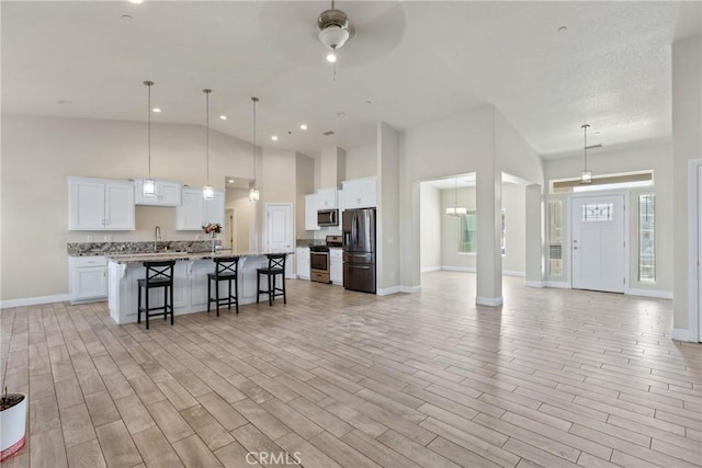 9121 6th Ave, Hesperia, CA 92345 - kitchen with stainless steel appliances, open floor plan, a kitchen breakfast bar, white cabinets, and a kitchen island with sink