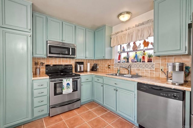 6548 Camino Del Parque, Carlsbad, CA 92011 - kitchen with appliances with stainless steel finishes, tile countertops, decorative backsplash, and light tile patterned floors