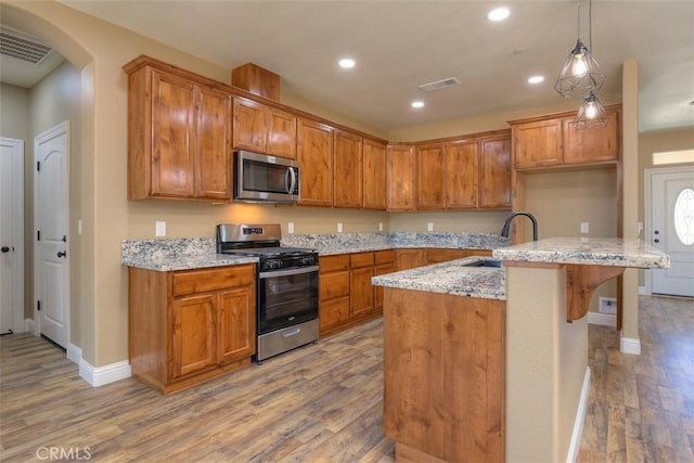 1910 Crandall Way, Paradise, CA 95969 - kitchen with appliances with stainless steel finishes, light wood finished floors, brown cabinets, arched walkways, and recessed lighting