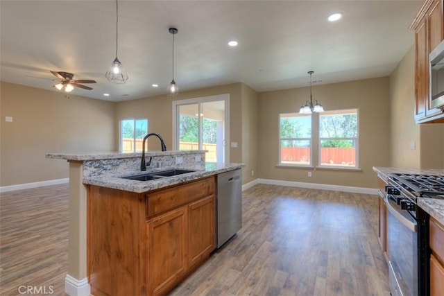 1910 Crandall Way, Paradise, CA 95969 - kitchen featuring stainless steel appliances, light wood-style flooring, brown cabinets, hanging light fixtures, and a kitchen island with sink