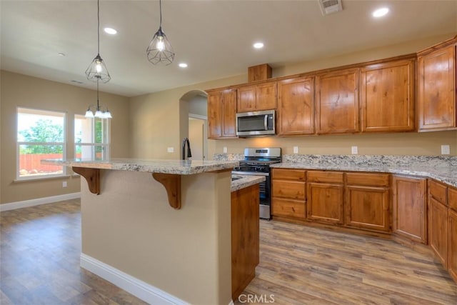 1910 Crandall Way, Paradise, CA 95969 - kitchen with appliances with stainless steel finishes, wood finished floors, a breakfast bar area, brown cabinets, and recessed lighting