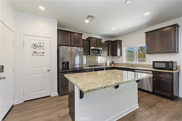 24329 Red Spruce Ave, Murrieta, CA 92562 - kitchen featuring appliances with stainless steel finishes, dark brown cabinetry, dark wood-style flooring, a kitchen island, and backsplash