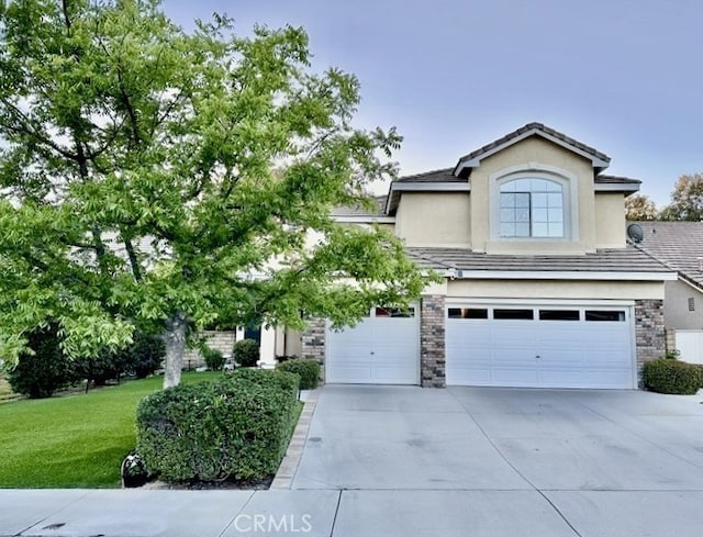 27448 Bridgewater Dr, Valencia, CA 91354 - view of front facade with an attached garage, concrete driveway, a front lawn, stone siding, and stucco siding