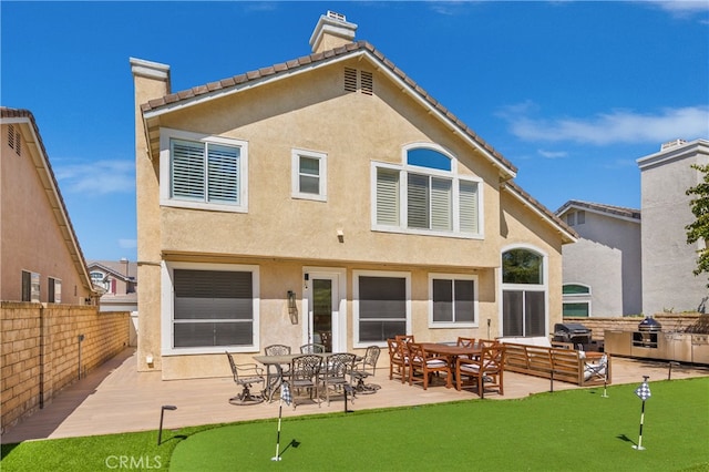 27448 Bridgewater Dr, Valencia, CA 91354 - back of house with a putting green, a chimney, stucco siding, and a patio area