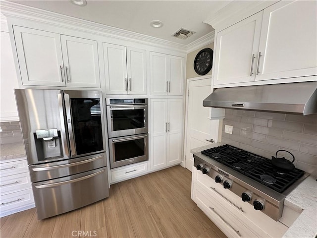 27448 Bridgewater Dr, Valencia, CA 91354 - kitchen with appliances with stainless steel finishes, under cabinet range hood, white cabinetry, decorative backsplash, and light wood-style flooring
