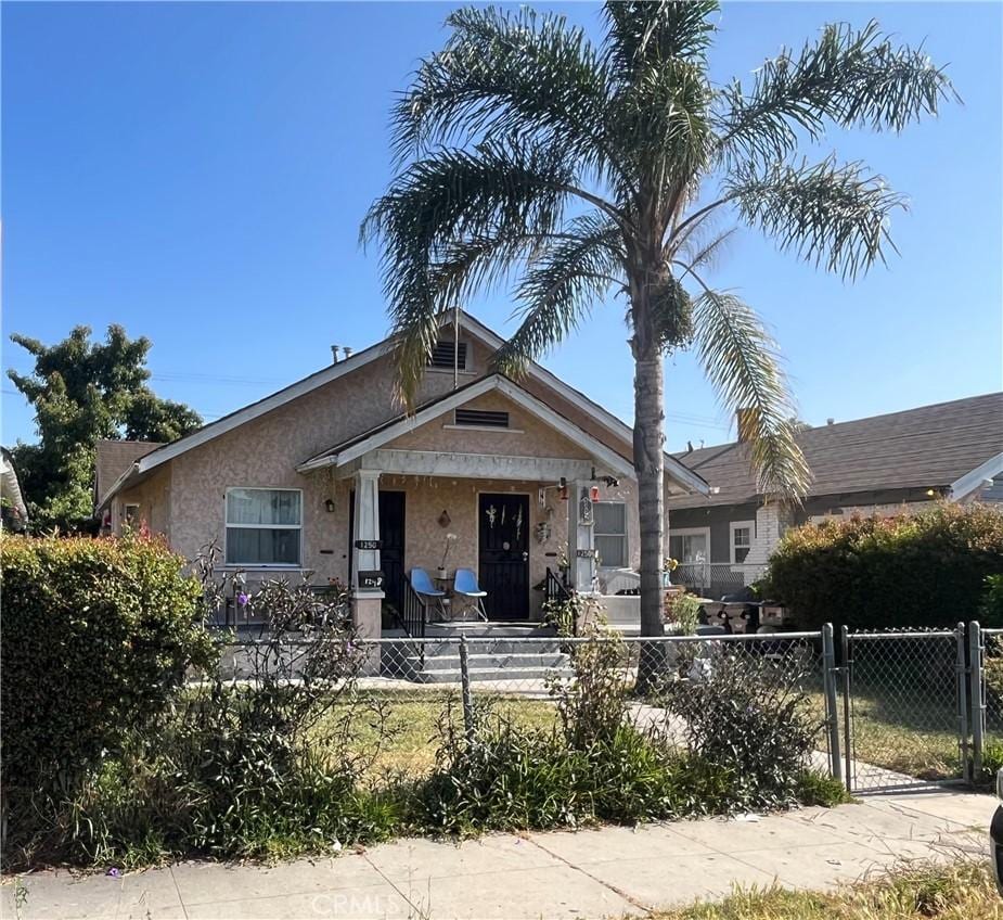 1248 Rolland Curtis Pl, Los Angeles, CA 90037 - view of front of house featuring a fenced front yard, stucco siding, a gate, and a porch