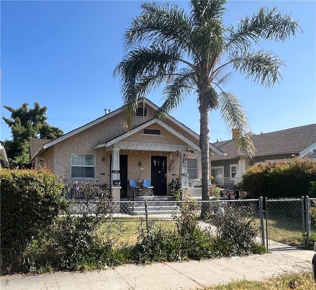 1248 Rolland Curtis Pl, Los Angeles, CA 90037 - view of front of house featuring a fenced front yard, stucco siding, a gate, and a porch