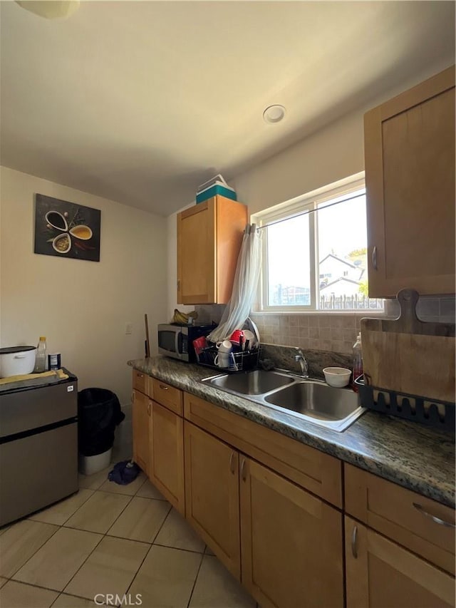 1248 Rolland Curtis Pl, Los Angeles, CA 90037 - kitchen with stainless steel microwave, light tile patterned floors, decorative backsplash, and dark countertops