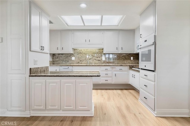 13300 Twin Hills Dr Unit 46A, Seal Beach, CA 90720 - kitchen featuring oven, light wood-style flooring, decorative backsplash, and white cabinets