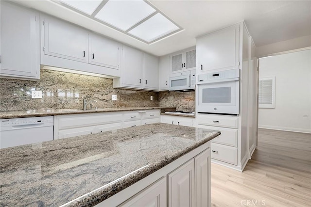 13300 Twin Hills Dr Unit 46A, Seal Beach, CA 90720 - kitchen with white appliances, light wood-type flooring, white cabinets, light stone counters, and backsplash