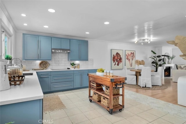 1200 Opal St Unit 7, Redondo Beach, CA 90277 - kitchen featuring ornamental molding, under cabinet range hood, light countertops, blue cabinets, and backsplash