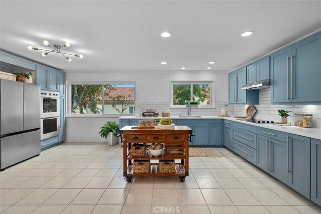 1200 Opal St Unit 7, Redondo Beach, CA 90277 - kitchen featuring freestanding refrigerator, blue cabinets, under cabinet range hood, light countertops, and backsplash