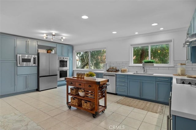 1200 Opal St Unit 7, Redondo Beach, CA 90277 - kitchen with appliances with stainless steel finishes, blue cabinets, tasteful backsplash, light countertops, and ornamental molding