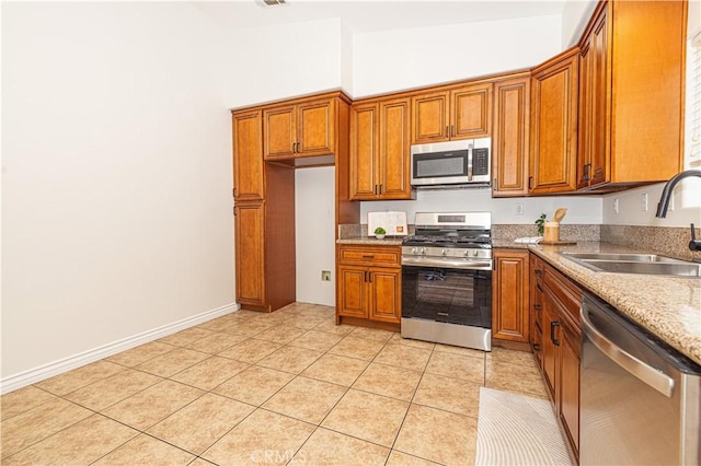 4158 Larchwood Pl, Riverside, CA 92506 - kitchen with appliances with stainless steel finishes, brown cabinets, light tile patterned floors, and light stone countertops
