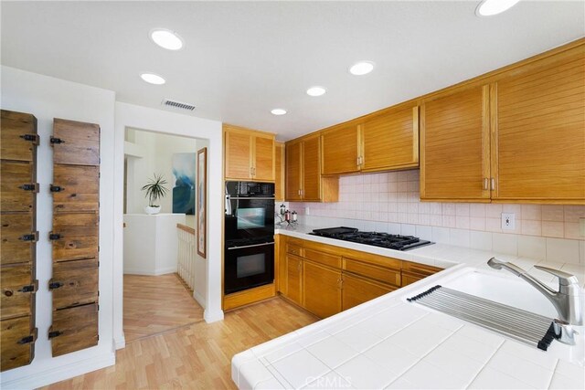 46 Saint Tropez, Laguna Niguel, CA 92677 - kitchen with black appliances, tile countertops, light wood-type flooring, tasteful backsplash, and recessed lighting