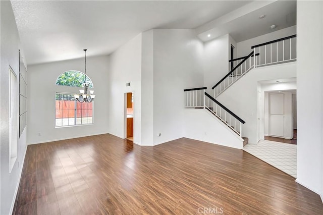 3115 Crowne Dr, Palmdale, CA 93551 - unfurnished living room featuring dark wood-style floors, a chandelier, high vaulted ceiling, and stairs