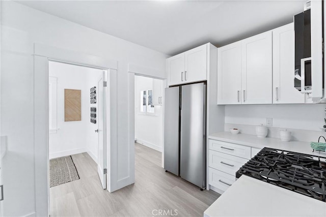 765 Loma Ave Unit 769, Long Beach, CA 90804 - kitchen with freestanding refrigerator, light countertops, white cabinets, and light wood finished floors