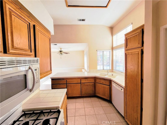 12429 Pocono Pl, Apple Valley, CA 92308 - kitchen featuring tile countertops, white appliances, brown cabinetry, a peninsula, and light tile patterned floors