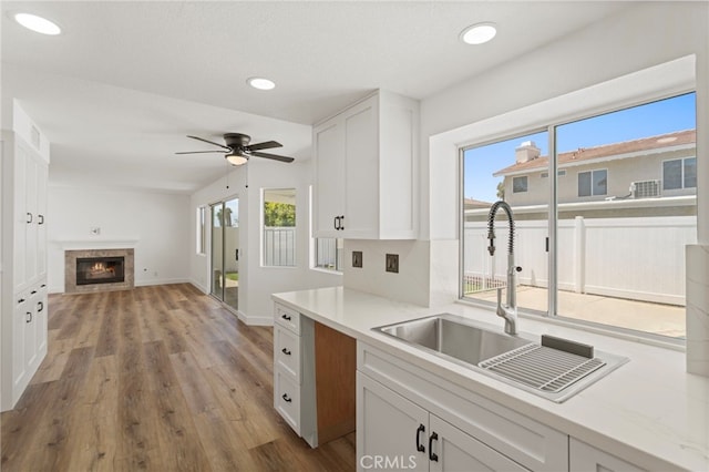 22710 Robin Way, Grand Terrace, CA 92313 - kitchen featuring white cabinetry, open floor plan, a glass covered fireplace, ceiling fan, and wood finished floors