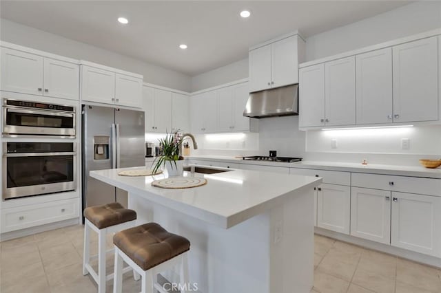 145 Sash, Irvine, CA 92618 - kitchen with under cabinet range hood, appliances with stainless steel finishes, light tile patterned flooring, a breakfast bar, and white cabinets