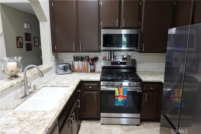 7262 Yellowtail Dr Unit 206, Huntington Beach, CA 92648 - kitchen with appliances with stainless steel finishes, backsplash, dark brown cabinetry, and light stone countertops