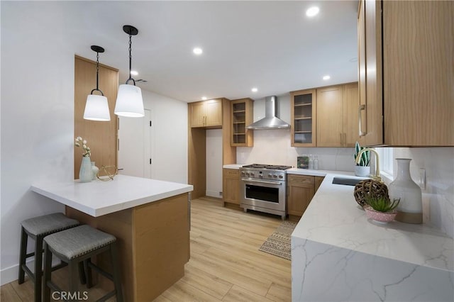 44 Seton Rd, Irvine, CA 92612 - kitchen with wall chimney exhaust hood, stainless steel stove, a peninsula, a breakfast bar, and glass insert cabinets