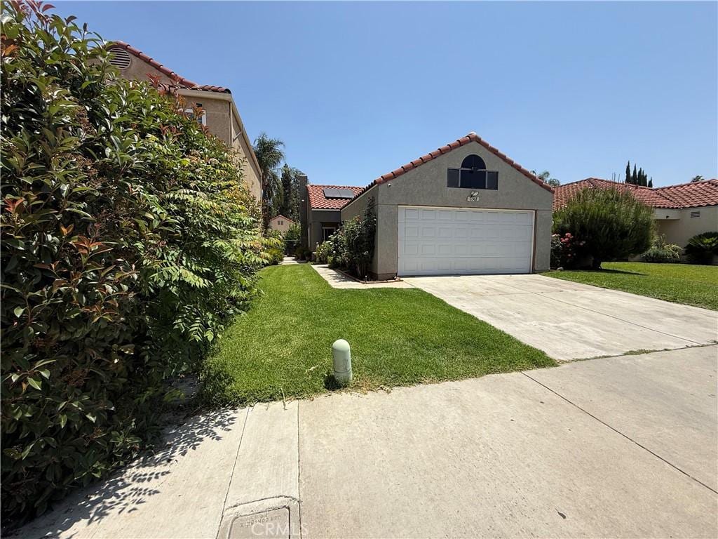 3567 Ganador Ct, Riverside, CA 92503 - mediterranean / spanish home featuring a front lawn, driveway, a tile roof, an attached garage, and stucco siding