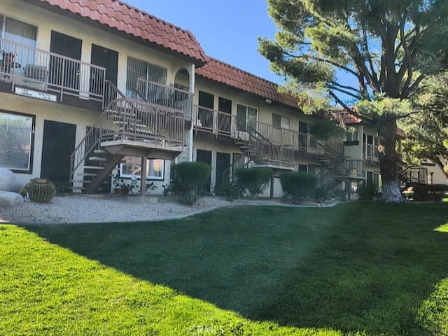 9647 Spyglass Ave Unit 18, Desert Hot Springs, CA 92240 - back of property with stairway, a tile roof, a lawn, and stucco siding