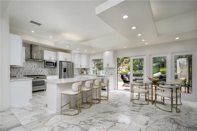 4557 Don Timoteo Dr, Los Angeles, CA 90008 - kitchen with stainless steel appliances, wall chimney range hood, decorative backsplash, a kitchen island, and light countertops