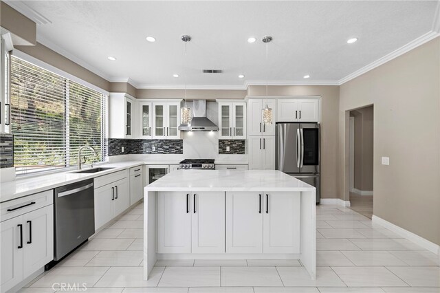 9 Cranwell, Aliso Viejo, CA 92656 - kitchen featuring stainless steel appliances, wall chimney exhaust hood, a center island, backsplash, and ornamental molding