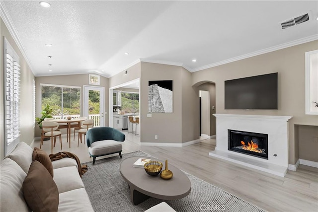 9 Cranwell, Aliso Viejo, CA 92656 - living room featuring arched walkways, light wood-style floors, recessed lighting, crown molding, and a glass covered fireplace