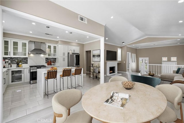 9 Cranwell, Aliso Viejo, CA 92656 - dining space featuring beverage cooler, recessed lighting, a warm lit fireplace, lofted ceiling, and crown molding