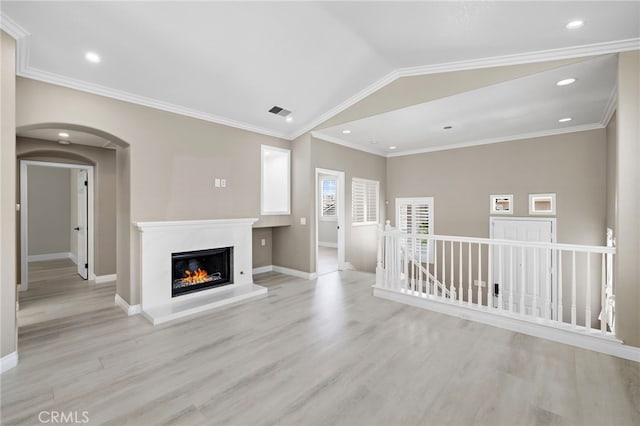 9 Cranwell, Aliso Viejo, CA 92656 - unfurnished living room with light wood finished floors, a glass covered fireplace, arched walkways, recessed lighting, and crown molding
