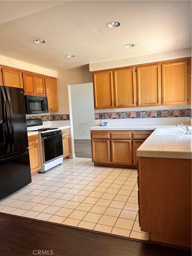 28499 Forest Oaks Way, Moreno Valley, CA 92555 - kitchen featuring black appliances, tile countertops, brown cabinets, a textured ceiling, and recessed lighting