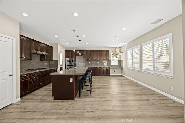 6792 Vanderbilt St, Chino, CA 91710 - kitchen with appliances with stainless steel finishes, tasteful backsplash, light wood-style floors, recessed lighting, and a kitchen island with sink