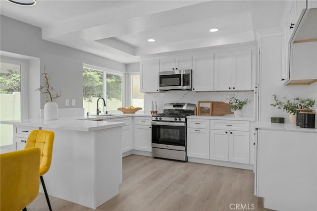 6923 Lamar Ct, Rancho Cucamonga, CA 91701 - kitchen featuring appliances with stainless steel finishes, white cabinets, a tray ceiling, a peninsula, and light countertops