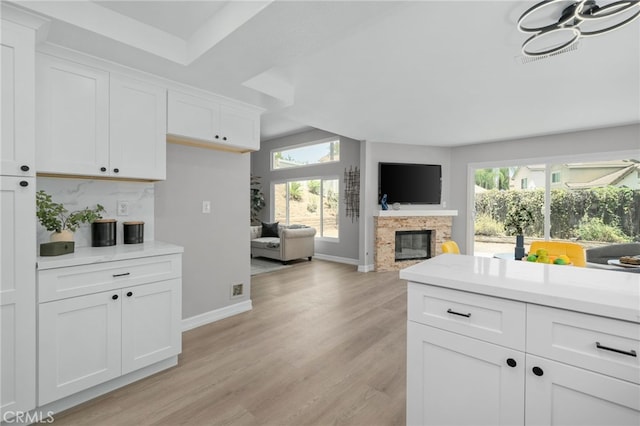 6923 Lamar Ct, Rancho Cucamonga, CA 91701 - kitchen featuring a glass covered fireplace, light wood finished floors, white cabinetry, and light countertops