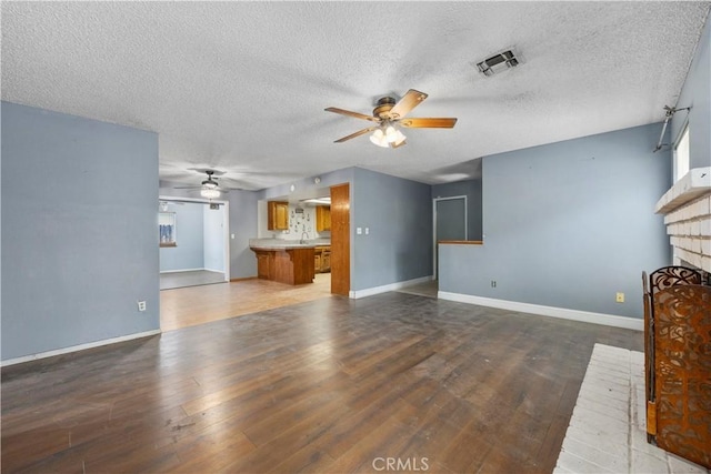 5013 Stancliff St, Bakersfield, CA 93307 - unfurnished living room featuring ceiling fan, a brick fireplace, wood finished floors, and a textured ceiling