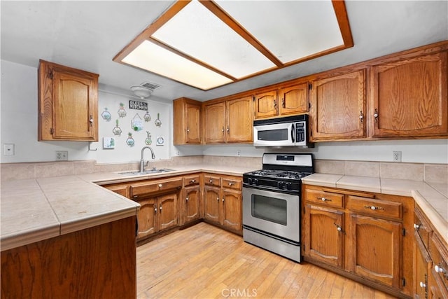 5013 Stancliff St, Bakersfield, CA 93307 - kitchen featuring stainless steel appliances, brown cabinetry, light wood-style flooring, and a peninsula