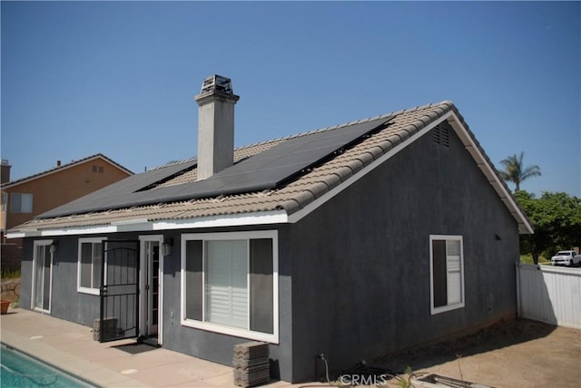 2007 Aberdeen Dr, Corona, CA 92881 - rear view of property featuring roof mounted solar panels, stucco siding, a patio, and a chimney