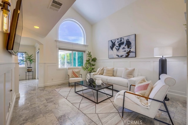 23851 Catamaran Way Unit 1, Laguna Niguel, CA 92677 - living room with a decorative wall, arched walkways, a wainscoted wall, light marble finish flooring, and high vaulted ceiling