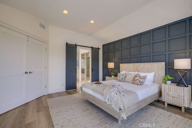 23851 Catamaran Way Unit 1, Laguna Niguel, CA 92677 - bedroom featuring a barn door, a decorative wall, vaulted ceiling, wood finished floors, and recessed lighting