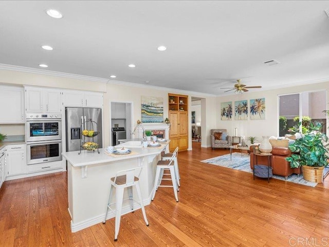 2381 Avenida Helecho, Carlsbad, CA 92009 - kitchen with stainless steel appliances, crown molding, white cabinetry, light wood-type flooring, and light countertops