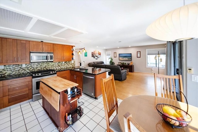 5963 Rio Valle Dr, Bonsall, CA 92003 - kitchen featuring appliances with stainless steel finishes, a peninsula, backsplash, brown cabinets, and open floor plan
