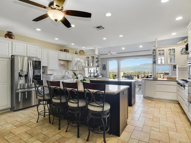 31755 Rancho Vista Rd, Temecula, CA 92592 - kitchen with stainless steel fridge with ice dispenser, a ceiling fan, an island with sink, a kitchen bar, and glass insert cabinets