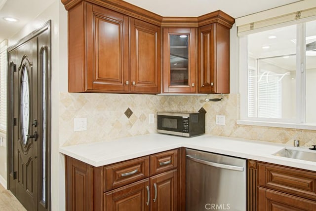 767 Calle Aragon Unit A, Laguna Woods, CA 92637 - kitchen featuring appliances with stainless steel finishes, glass insert cabinets, light countertops, tasteful backsplash, and brown cabinets