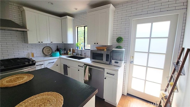 143 Warren Ave, Santa Paula, CA 93060 - kitchen featuring stainless steel appliances, wall chimney range hood, backsplash, white cabinets, and wood finished floors