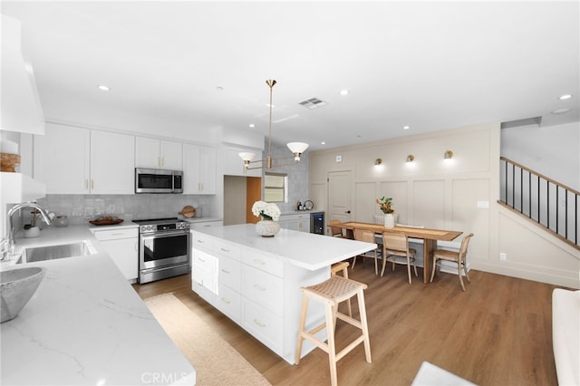 16221 Orizaba Ave, Paramount, CA 90723 - kitchen with appliances with stainless steel finishes, decorative backsplash, white cabinetry, light stone countertops, and recessed lighting