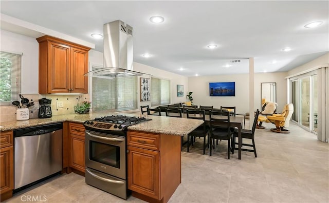 617 Iris Ave, Corona Del Mar, CA 92625 - kitchen featuring appliances with stainless steel finishes, island range hood, brown cabinetry, a peninsula, and light stone countertops