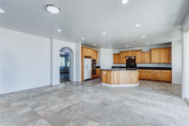 35050 Margo Rd, Lake Elsinore, CA 92530 - kitchen featuring white fridge with ice dispenser, arched walkways, dark countertops, recessed lighting, and under cabinet range hood
